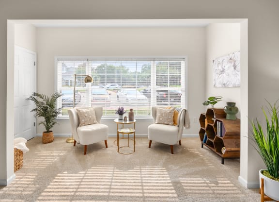 a living room with two white chairs and a table in front of a large window at Abberly Grove Apartment Homes, Raleigh, NC