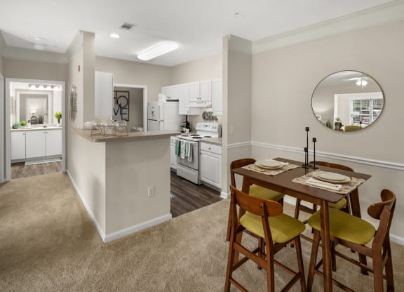 a dining area with a table and chairs and a kitchen in the background at Abberly Grove Apartment Homes, Raleigh, 27610