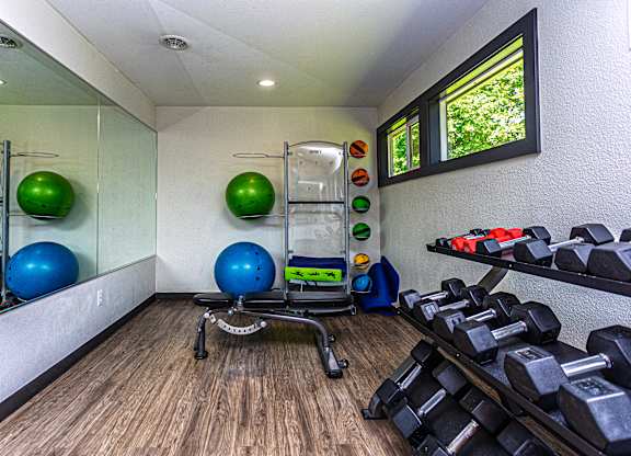 A gym room with a mirror, exercise balls, dumbbells, and a bench.