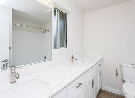 A white bathroom with a toilet, sink, and mirror.