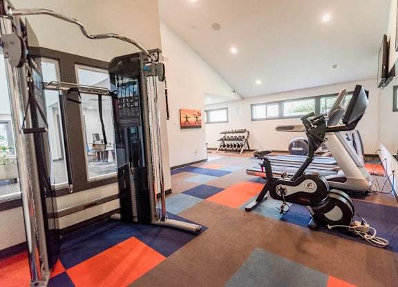 A gym with a variety of equipment including a treadmill, a stationary bike, and a weight machine at Altitude Apartment, Tacoma, WA, 98444