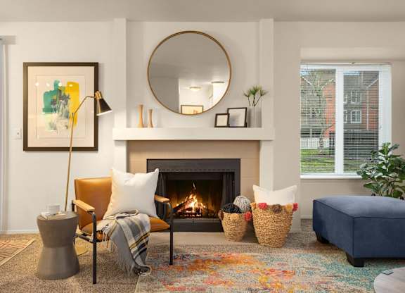 A living room with a fireplace, a chair, a couch, and a painting on the wall.