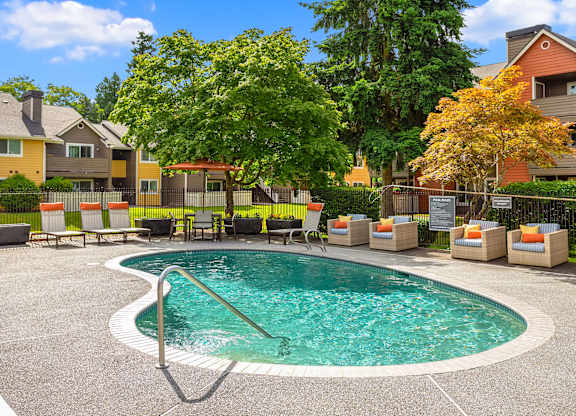 A small pool surrounded by chairs and trees.