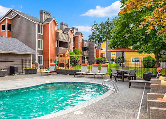 A swimming pool surrounded by chairs and buildings.