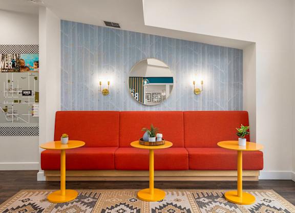 A red sofa with two yellow tables in front of it.