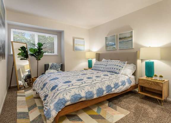A bedroom with a bed, two lamps, and a rug.