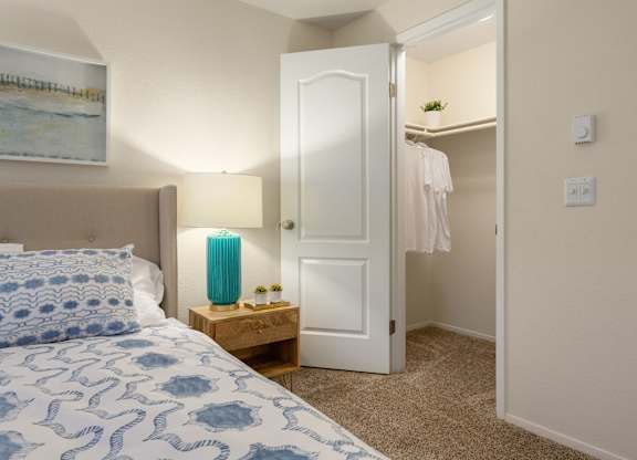 A bedroom with a bed, nightstand, and closet.
