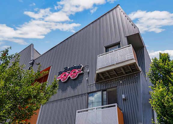 A modern building with a grey facade and a bicycle logo on the side.