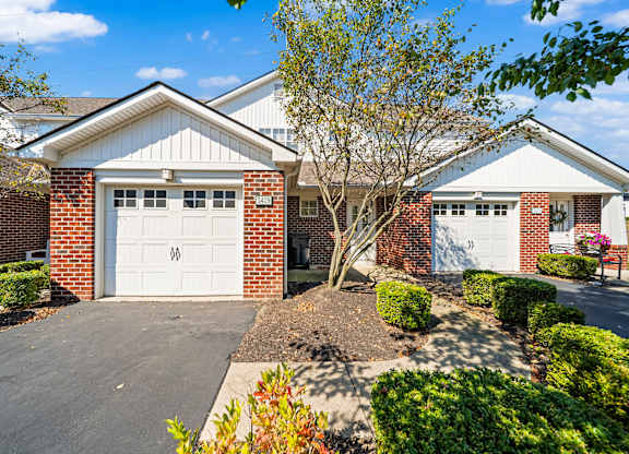 A house with a white garage door and a tree in front.