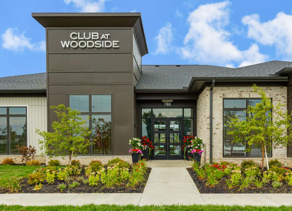 the front of a club at woodside building with a sidewalk and plants
