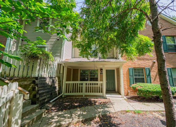 front entrance of a house with a porch and tree