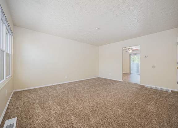 A room with a carpeted floor and a window with blinds.