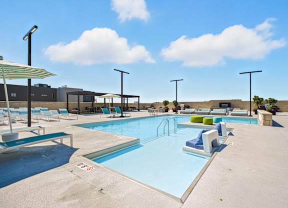 A large outdoor swimming pool with sun loungers and umbrellas.