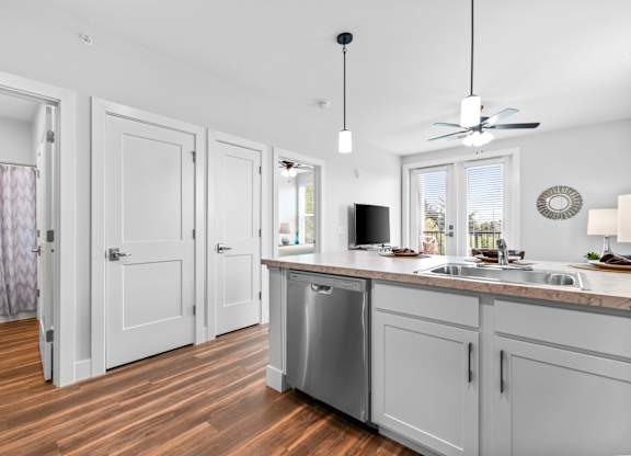 A kitchen with white cabinets and a wooden floor.