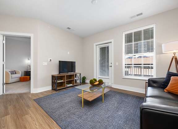 A living room with a black leather couch, a wooden coffee table, and a flat-screen TV.