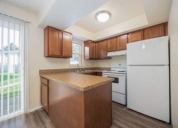 A kitchen with white appliances and wooden cabinets.