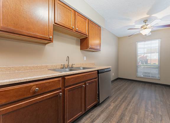 A kitchen with wooden cabinets and a ceiling fan.