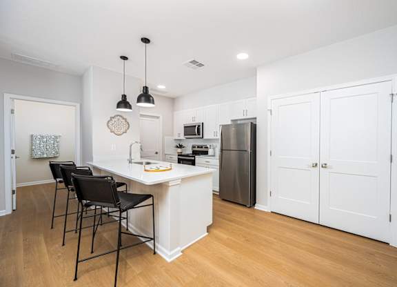 A kitchen with white cabinets and a white island with a counter top.