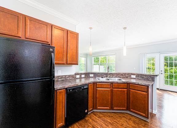 A black fridge in a kitchen with wooden cabinets.