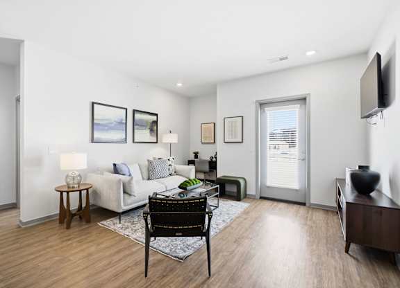 A living room with a white couch, a coffee table, and a television.