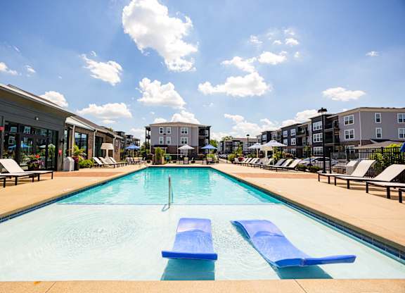 A swimming pool with blue loungers and a cloudy sky.