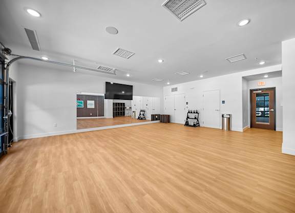 A spacious room with wooden flooring and white walls.