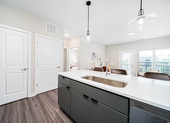 A kitchen with a white counter top and dark wood floors.