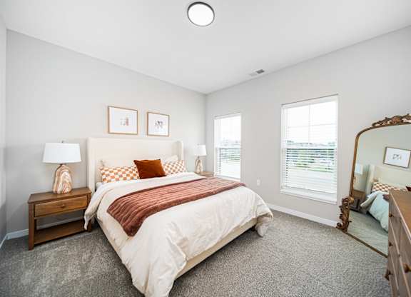 A bedroom with a large bed and a mirror on the wall.