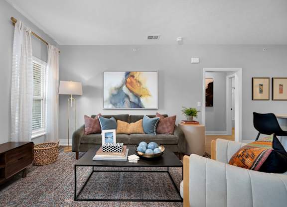 A living room with a couch, a coffee table, and a painting on the wall.