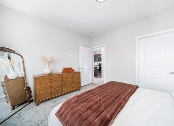A bedroom with a large bed and a wooden dresser.