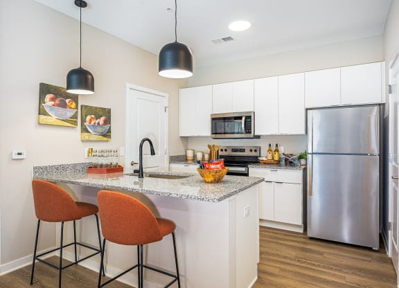 a kitchen with stainless steel appliances and a counter with two stools