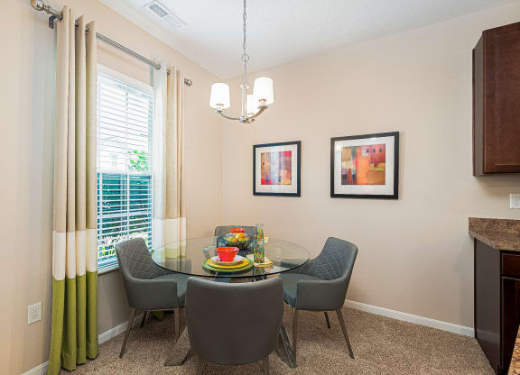 a dining room with a glass table and chairs and a window