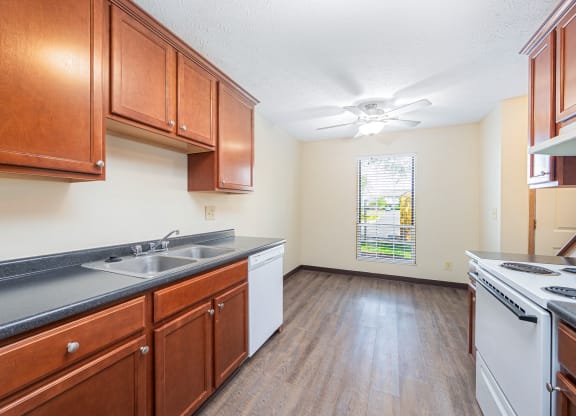 a kitchen with wooden cabinets and white appliances and a window