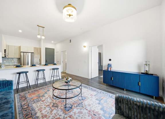 A living room with a blue sofa and a rug.