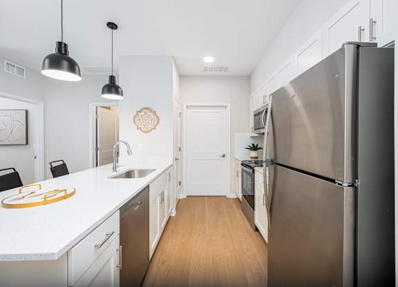 A modern kitchen with a stainless steel refrigerator and wooden floors.
