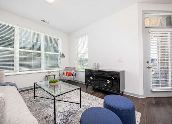 A living room with a glass coffee table and a grey sofa.