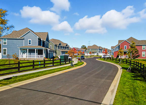A residential street with houses on both sides and a clear blue sky above.
