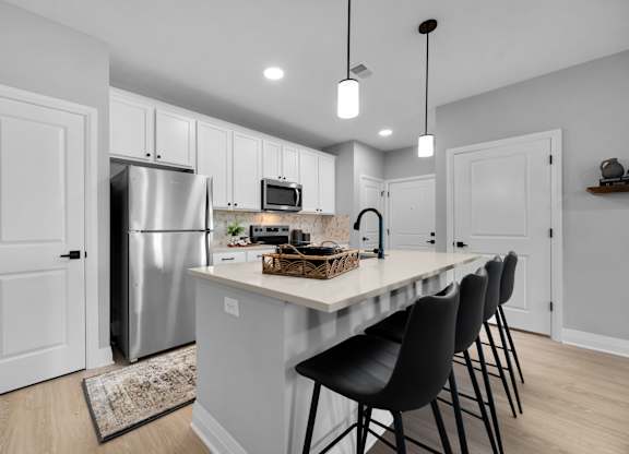 A kitchen with a white island and black chairs.