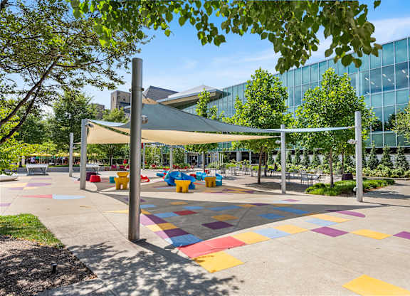 A playground with a white canopy and colorful tiles on the ground.