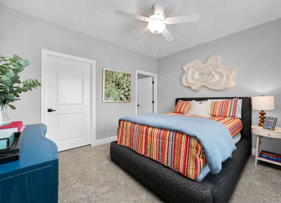 A bedroom with a bed, nightstand, and a ceiling fan.