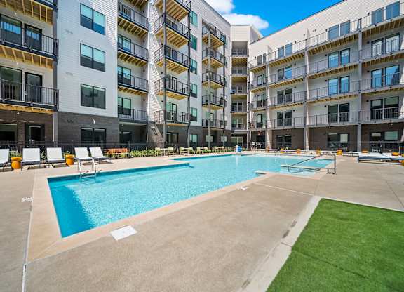 A large swimming pool is surrounded by apartment buildings.