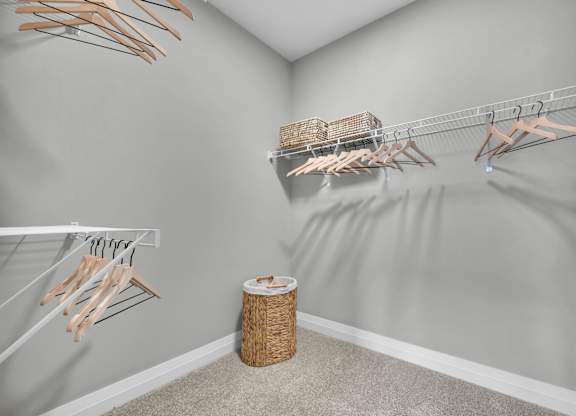 A room with a grey wall and a white shelf with clothes hangers.
