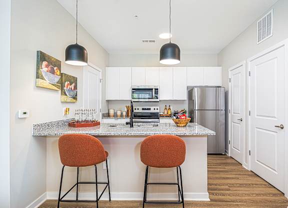 A kitchen with a white countertop and orange barstools.