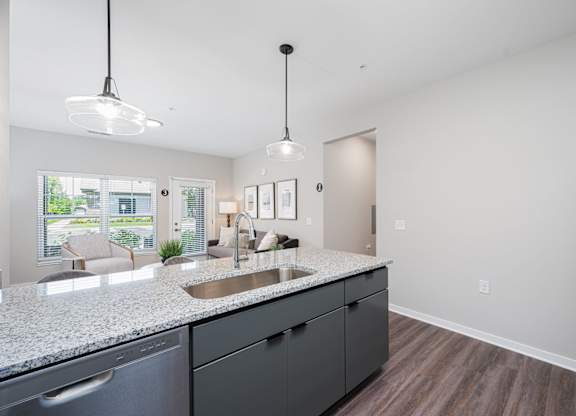 A kitchen with a granite countertop and a refrigerator on the right.