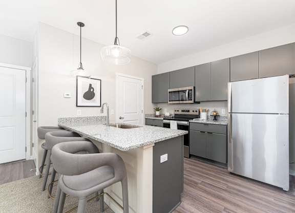 A kitchen with a white counter top and grey chairs.