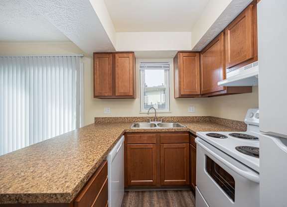 A kitchen with brown cabinets and a white stove top oven.