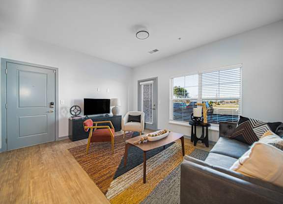 A living room with a grey door and a brown sofa.