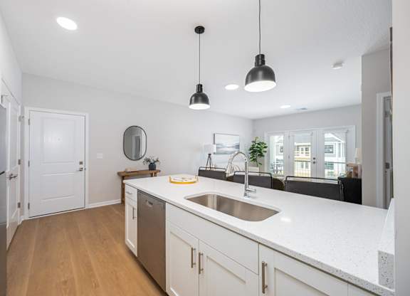 A kitchen with white countertops and wooden floors.