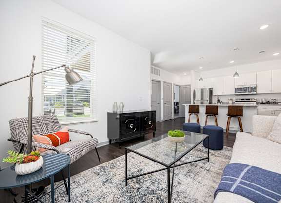 A modern living room with a glass coffee table and a grey sofa.