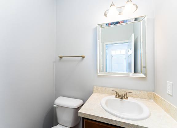 A bathroom with a toilet, sink and mirror.